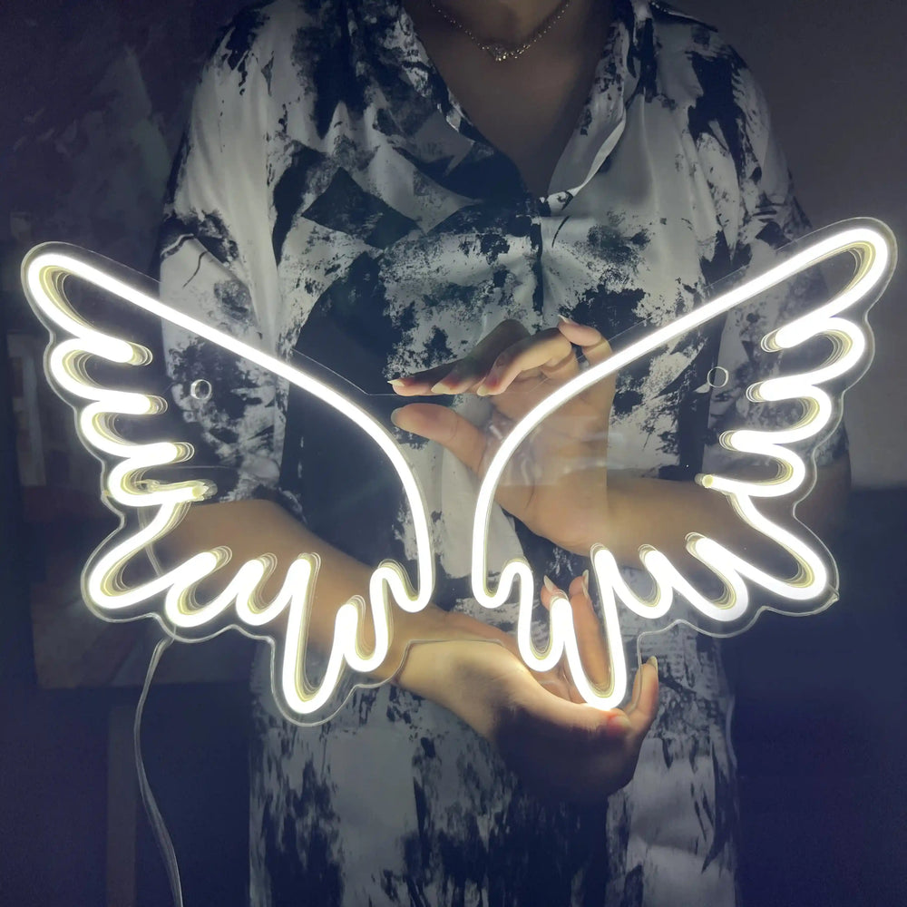 A girl holding a custom neon sign of white color in the shape of angel wings | ManhattanNeons