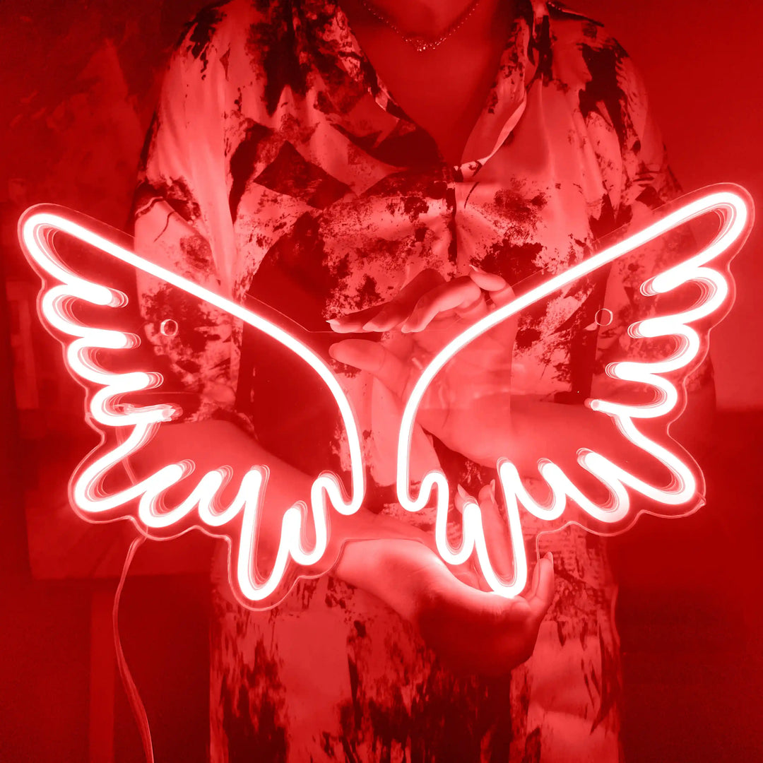 A girl holding a custom neon sign of red color in the shape of angel wings | ManhattanNeons