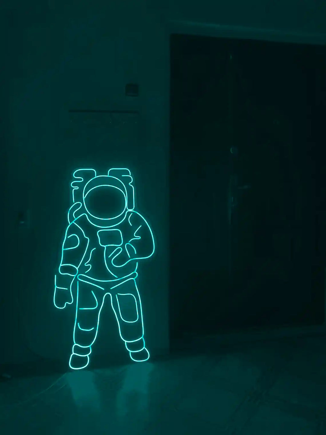 Teal colored Astronaut LED Neon Sign placed on the floor beside a door - from manhattonneons.com.