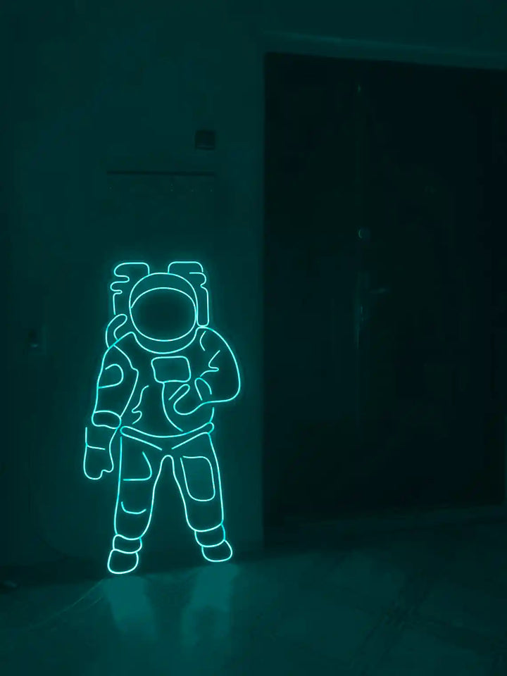 Teal colored Astronaut LED Neon Sign placed on the floor beside a door - from manhattonneons.com.