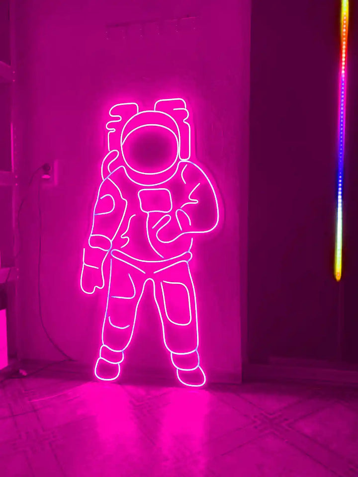 Pink colored Astronaut LED Neon Sign placed on the floor beside a door - from manhattonneons.com.